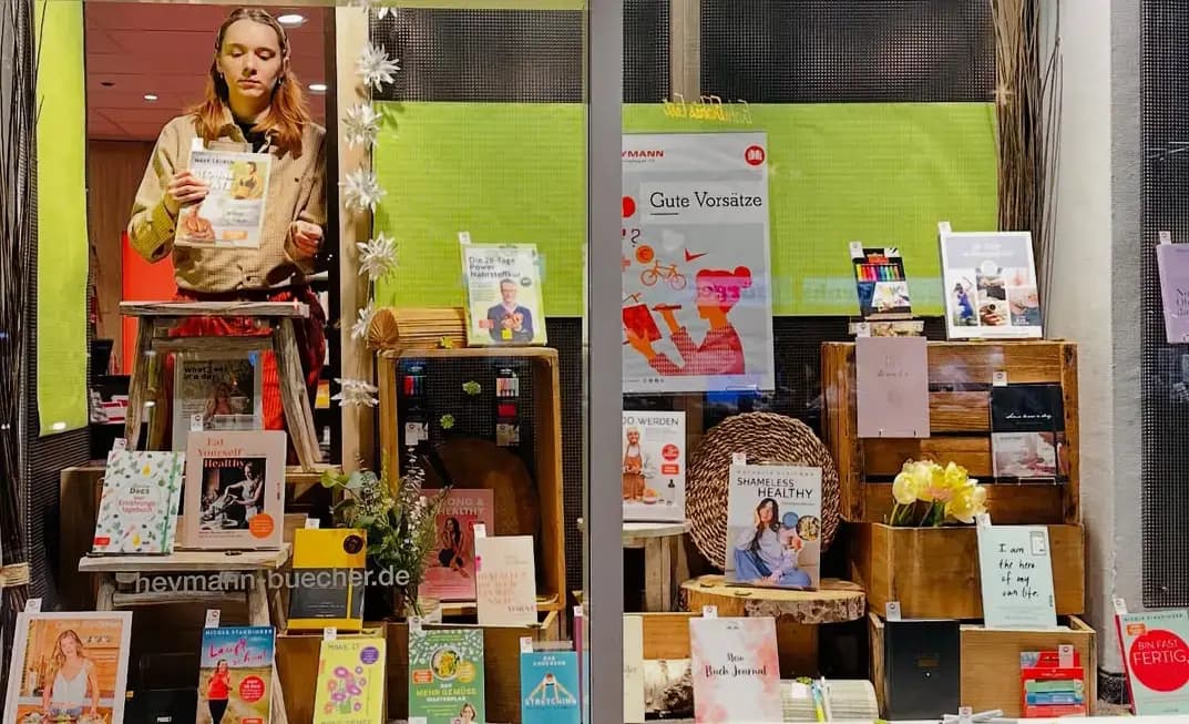 Eine Heymann-Kollegin dekoriert liebevoll ein Schaufenster der Buchhandlung.