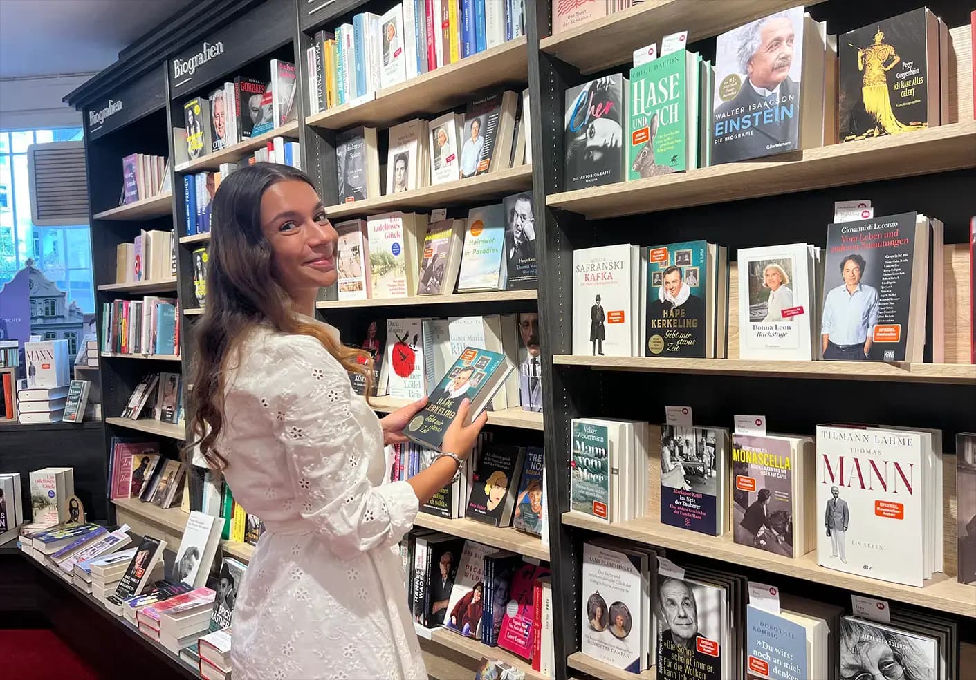 Zwei Kolleginnen bei Heymann stehen an einem Büchertisch und diskutieren lächelnd über ein Buch, was die Leidenschaft im Team zeigt.