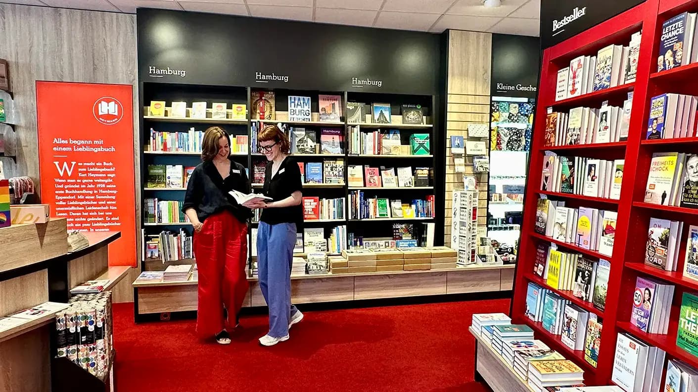 Zwei Heymann-Mitarbeiterinnen arbeiten am Informationstresen einer Buchhandlung und zeigen den teamorientierten Service.