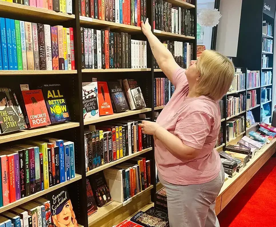 Eine Heymann-Mitarbeiterin sortiert Bücher in ein Regal ein.